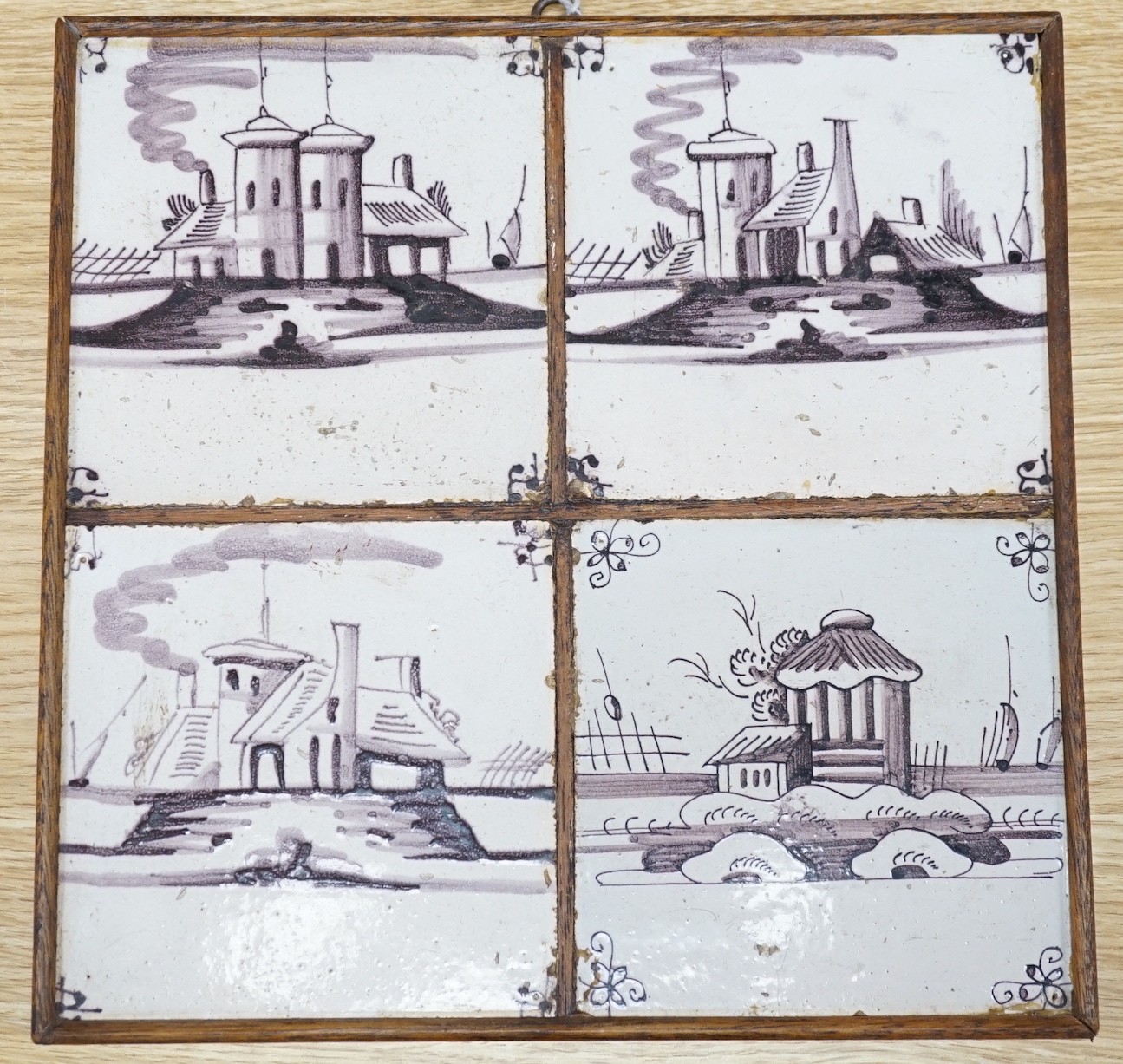 A set of four 18th century Dutch Delft manganese tiles decorated with buildings by a canal (frame 27cm)